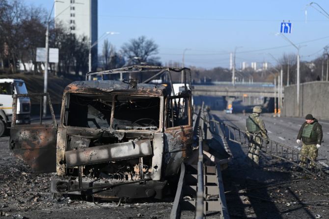 Soldados ucranianos frente a un vehículo del ejército ucraniano quemado en el lado oeste de la capital ucraniana de Kyiv el 26 de febrero de 2022. -.