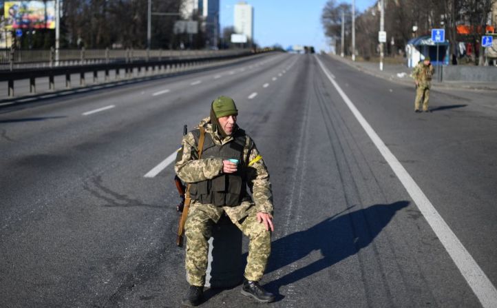 Un miembro del servicio ucraniano sostiene una taza de té mientras patrulla la carretera vacía en el lado oeste de la capital ucraniana de Kyiv en la mañana del 26 de febrero de 2022. -.