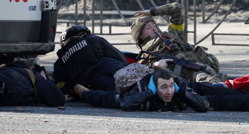 La gente en Kyiv se pone a cubierto cuando suena una sirena antiaérea el 26 de febrero cerca de un edificio de apartamentos que resultó dañado por los bombardeos.