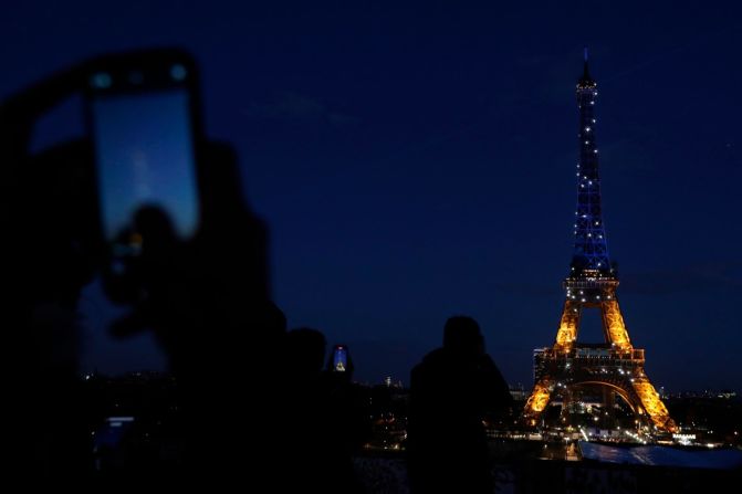 Gente fotografía la Torre Eiffel de París mientras se ilumina con los colores de Ucrania el 25 de febrero.