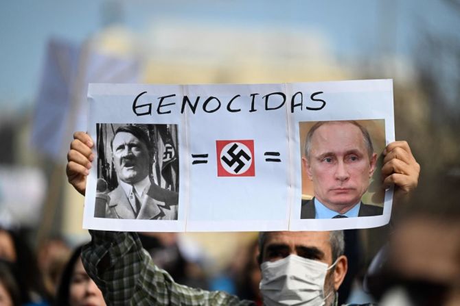 Un manifestante sostiene un cartel que representa al presidente ruso Vladimir Putin y Adolf Hitler con la palabra "genocidas" durante una protesta contra la invasión rusa de Ucrania en Madrid el 27 de febrero de 2022.