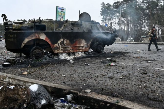 Un hombre armado pasa junto a un vehículo militar quemado en un puesto de control en la ciudad de Brovary, en las afueras de Kyiv, el 1 de marzo de 2022, tras el ataque de las tropas rusas en suelo ucraniano.