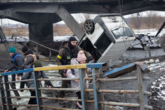 Un militar ucraniano ayuda a un niño a cruzar el puente destruido el 1 de marzo de 2022 en Irpin, Ucrania, mientras las fuerzas rusas continuaban avanzando sobre la capital de Ucrania.