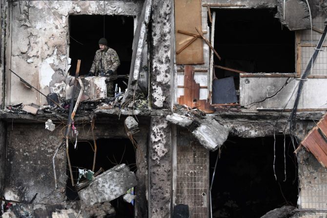 Un militar ucraniano se ve en la ventana de un edificio residencial destruido donde un proyectil militar ruso cayó, destruyendo el edificio. El ataque aéreo desplazó en los primeros días, alíenos unas 100.000 personas.