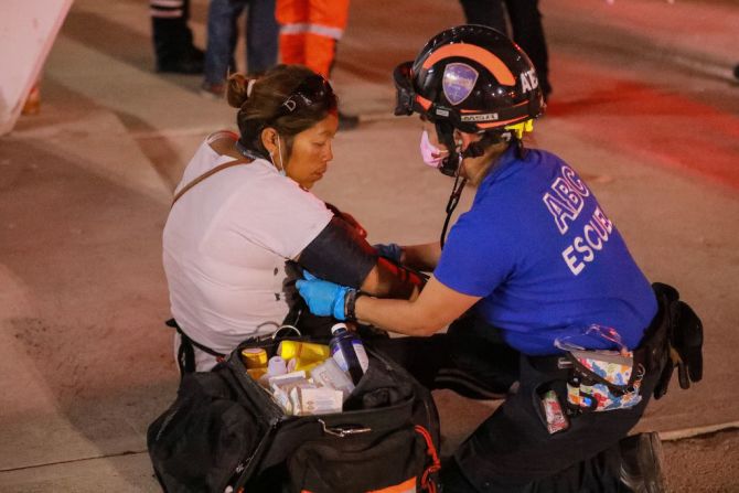 Una paramédico ayuda a una mujer mientras las ambulancias atienden a las personas heridas por los disturbios.