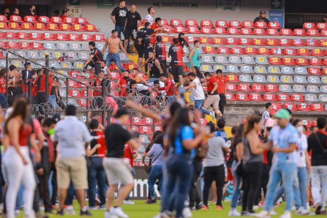 Los aficionados del Atlas intentan huir de una pelea contra los aficionados de los Gallos Blancos del Querétaro durante el partido de la Liga MX.