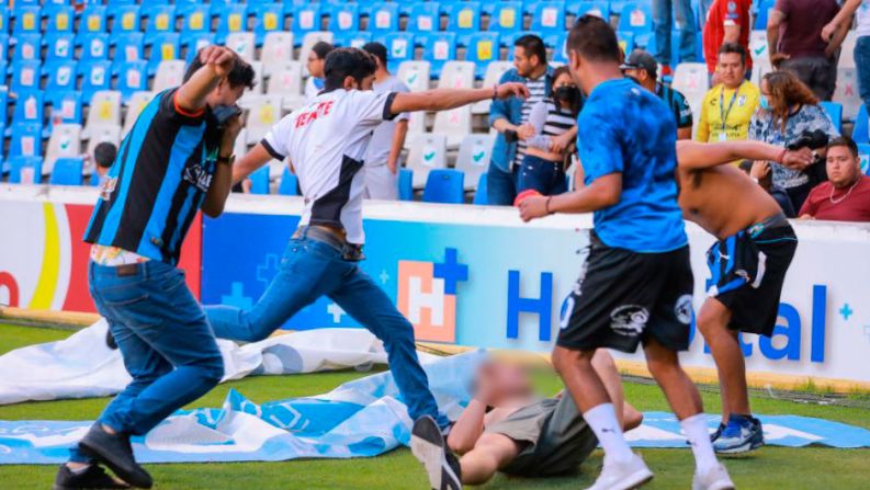 Los aficionados se golpean en la cancha durante el partido entre el Atlas y los Gallos Blancos de Querétaro en el estadio La Corregidora.