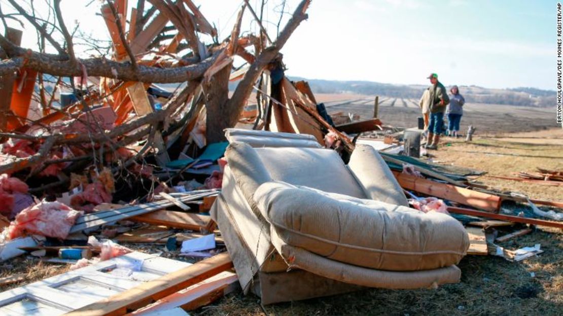 Personas caminan entre escombros este lunes, mientras se realizan los esfuerzos de limpieza en Winterset, Iowa, después de que un tornado azotara el área este sábado.