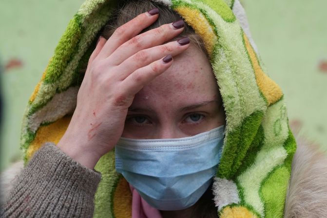 Una mujer sale del hospital sosteniendo su cabeza con la mano.