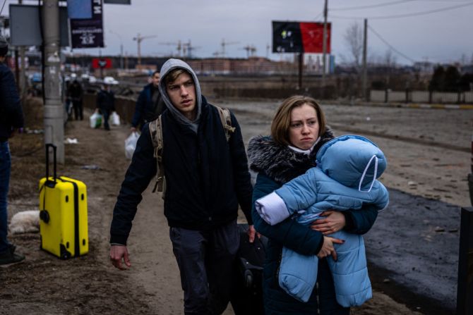 Una mujer lleva a su hijo mientras huyen de la ciudad de Irpin, al noroeste de Kyiv, el 7 de marzo de 2022. - Ucrania desestimó el lunes la oferta de Moscú de establecer corredores humanitarios desde varias ciudades bombardeadas, tras conocerse que algunas rutas llevarían a los refugiados a Rusia o Belarús. La propuesta rusa de un pasaje seguro desde Járkiv, Kyiv, Mariupol y Sumy se produjo después de que civiles ucranianos aterrorizados fueran atacados en anteriores intentos de alto el fuego.