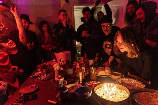 La gente comparte la cena y canta el "Feliz cumpleaños" durante una celebración en Kyiv el 20 de marzo. Este espacio de estudio se ha convertido en un refugio antiaéreo para aproximadamente 25 artistas que se ofrecen como voluntarios para ayudar en la guerra.