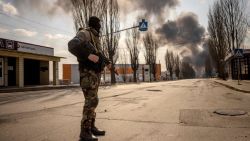 TOPSHOT - A Ukrainien serviceman stands guard near a burning warehouse hit by a Russian shell in the suburbs of the capital Kyiv on March 24, 2022. - The UN General Assembly on March 24, 2022, adopted a new non-binding resolution that demanded an "immediate" halt to Russia's war in Ukraine. At UN headquarters in New York, 140 countries voted in favor, 38 abstained and five voted against the measure, with applause ringing out afterwards. (Photo by FADEL SENNA / AFP)