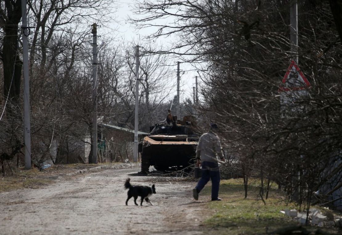 Un residente local camina frente a un vehículo blindado de transporte de personal (APC) ruso destruido en un pueblo en la línea del frente de la parte norte de la región de Kyiv el 28 de marzo de 2022.