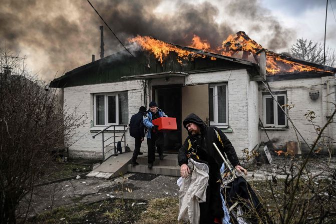 Personas sacan sus pertenencias de una casa en llamas el 4 de marzo tras un intenso bombardeo ruso en la ciudad. Crédito: Aris Messinis/AFP/Getty Images