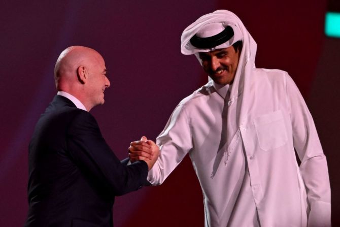 El presidente de la FIFA, Gianni Infantino (izquierda), le da la mano al emir jeque Tamim bin Hamad al-Thani (derecha) de Qatar en el escenario durante el sorteo de la Copa del Mundo de 2022.