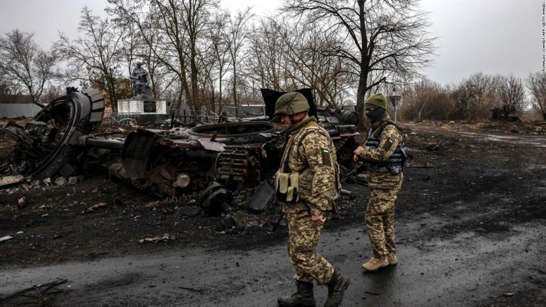 Soldados ucranianos patrullan junto a un tanque ruso destruido en la aldea de Lukianivska, cerca de Kyiv, el 30 de marzo de 2022.