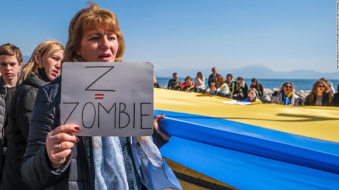 Una mujer sostiene un cartel que dice "Z = Zombie" en una marcha en Nápoles, Italia.