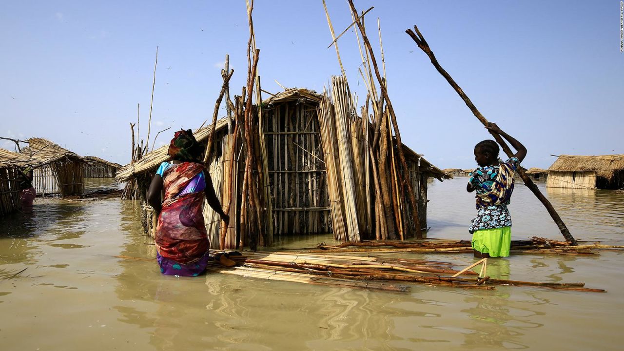 TOPSHOT - South Sudanese refugees try to repair their hut in flooded waters from the White Nile at a refugee camp which was inundated after heavy rain near in al-Qanaa in southern Sudan, on September 14, 2021. - Nearly 50 villages have been submerged in southern Sudan, displacing some 65,000 people including South Sudanese refugees whose camp was inundated, the UN said in a report last week. (Photo by ASHRAF SHAZLY / AFP)