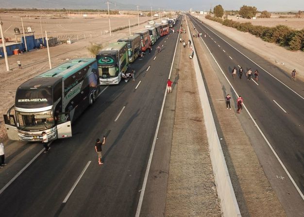 Autobuses estacionados y personas que caminan por la carretera Panamericana durante el bloqueo vial en Ica, en el sur de Perú, el 4 de abril de 2022.