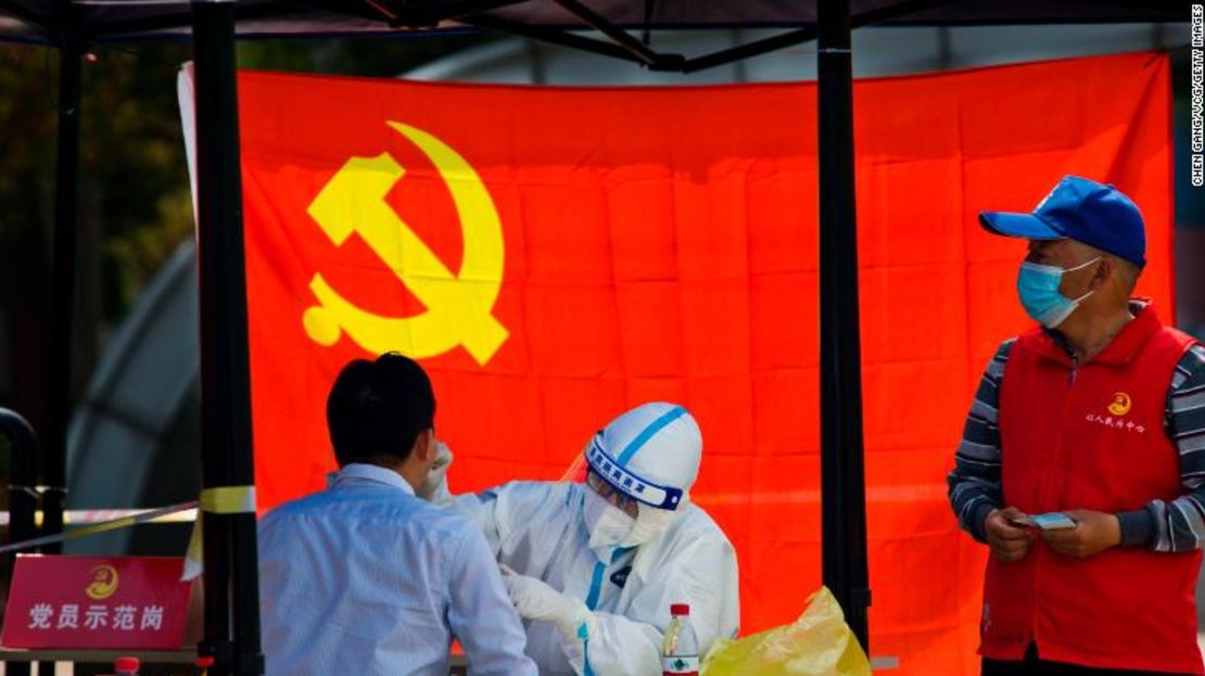 Un trabajador médico examina a un residente por covid-19 frente a una bandera del Partido Comunista de China el 12 de abril de 2022, en la ciudad de Zhenjiang, de la provincia de Jiangsu.