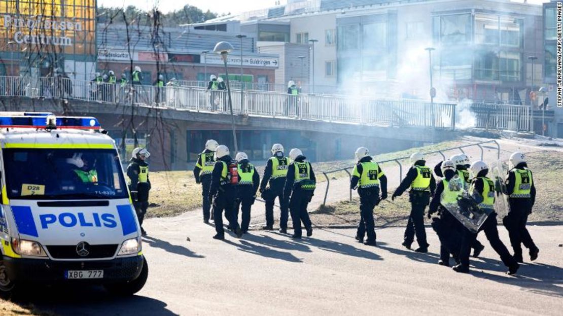 La policía antidisturbios pasa una barricada para ingresar a un centro comercial durante los incidentes en Norrköping el domingo.