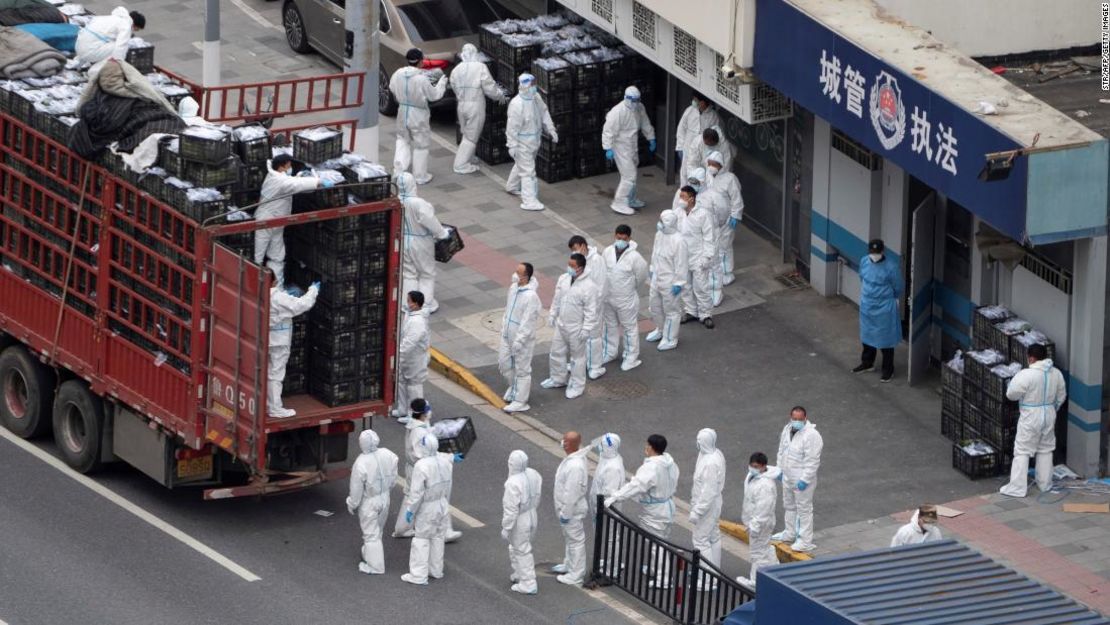 Trabajadores con trajes de protección contra materiales peligrosos transfieren suministros diarios de alimentos y necesidades para los residentes locales durante el confinamiento por covid-19 en Shanghái.