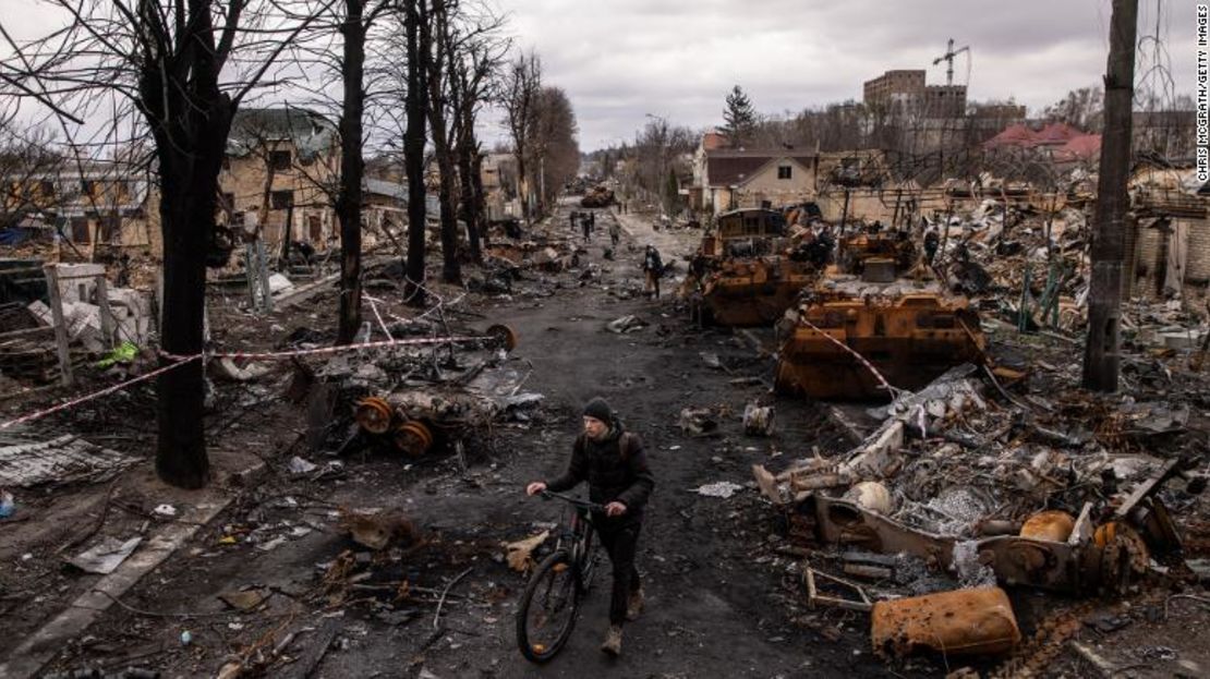 Un hombre empuja su bicicleta a través de los escombros y destruye vehículos militares rusos en una calle el 6 de abril de 2022 en Bucha, Ucrania.