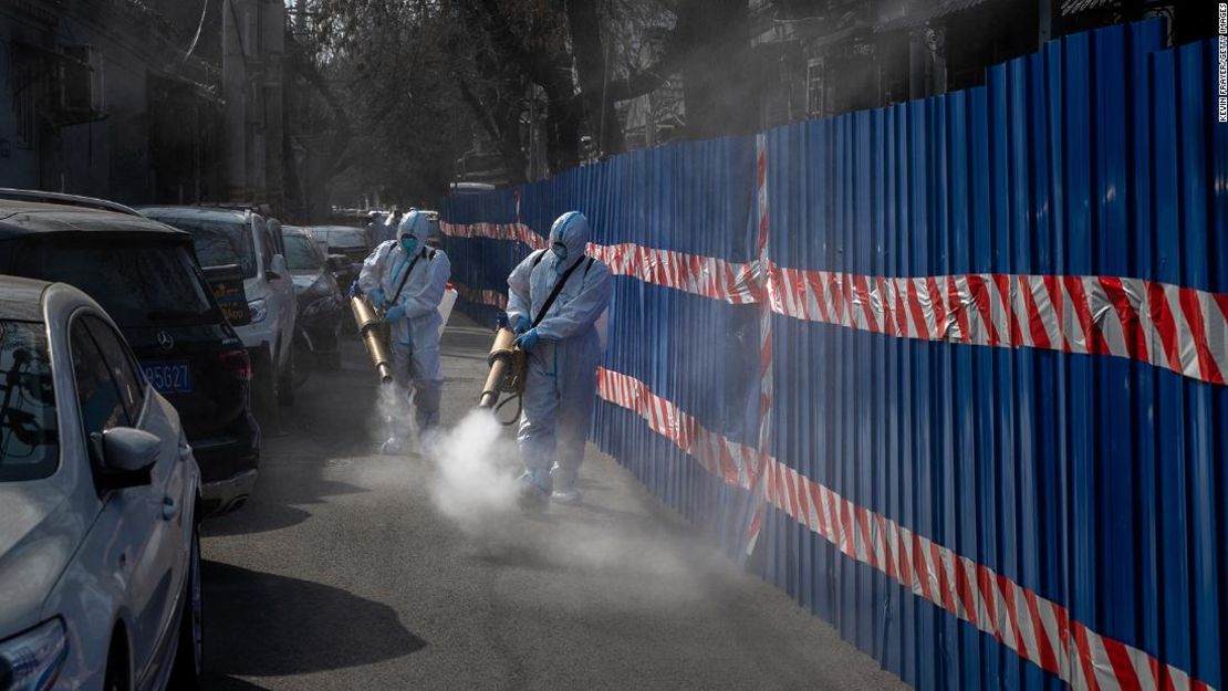 Trabajadores con trajes de protección desinfectan una zona fuera de una comunidad cerrada después de que se encontraran casos recientes de covid-19 en la zona, el 28 de marzo, en Beijing, China.