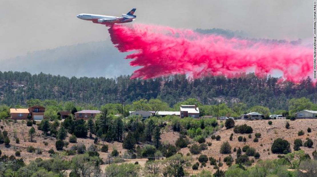 Un avión vierte retardante de fuego cerca del incendio Hermit Peak y casas en el lado oeste de Las Vegas, Nuevo México, el martes.