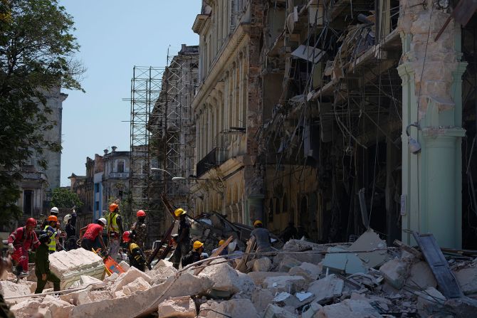 Trabajadores de emergencia caminan entre los escombros afuera del Hotel Saratoga luego de una explosión en La Habana el 6 de mayo.