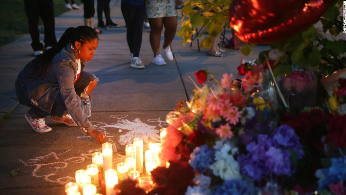 Una mujer escribe un mensaje con tiza el domingo, durante un homenaje improvisado afuera del supermercado Tops en Buffalo.