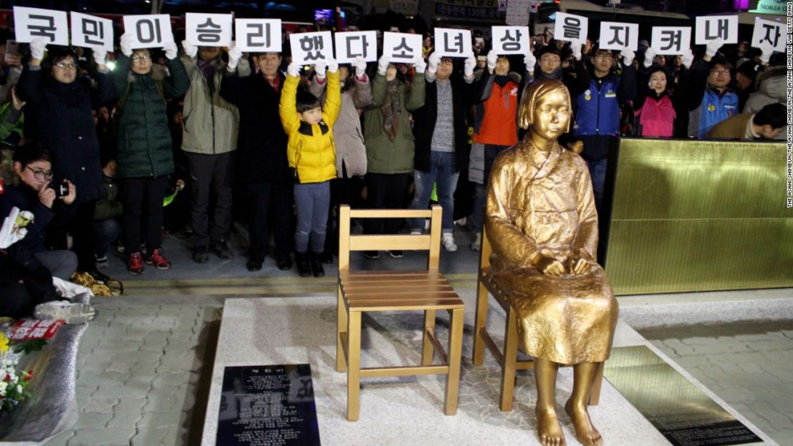 Manifestantes y la estatua de una niña que simboliza a las "mujeres de confort" coreanas frente al consulado general de Japón en Busan, Corea del Sur, el 31 de diciembre de 2016.