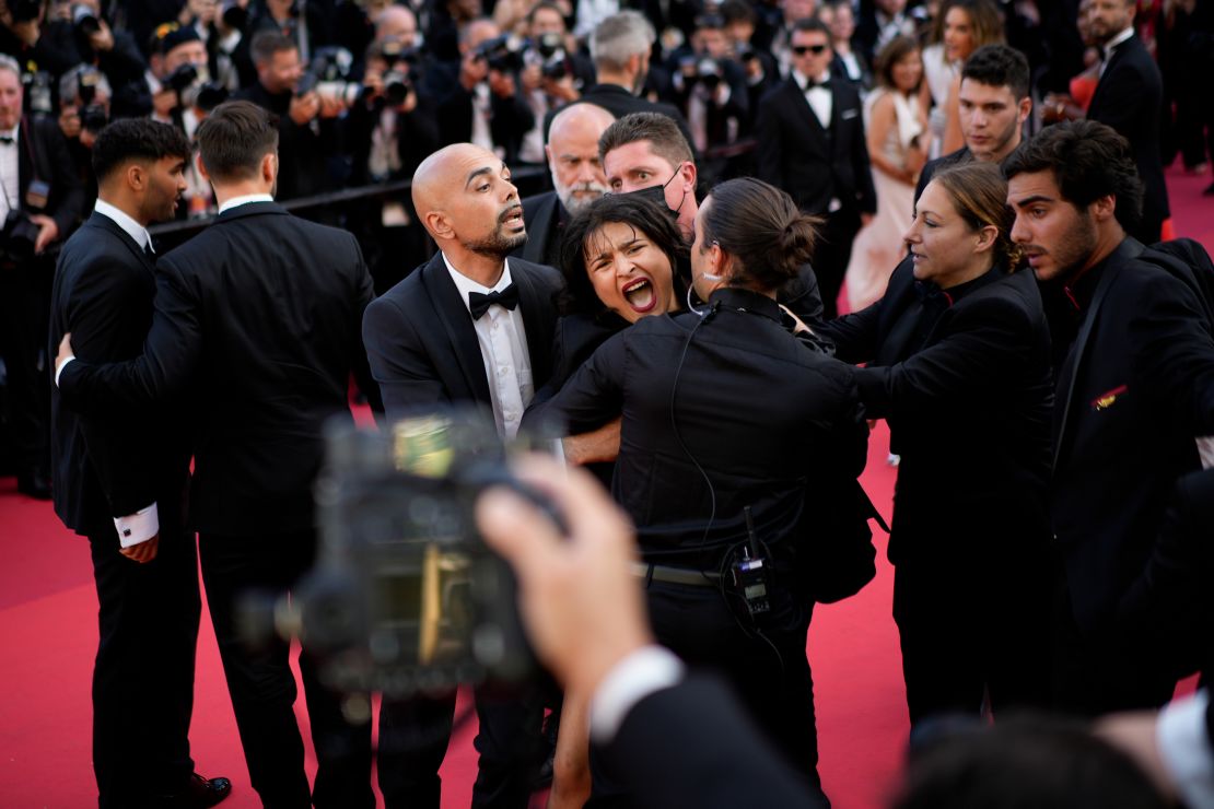 Los guardias de seguridad cubren a una manifestante "topless" después de que corrió hacia la alfombra roja en el Festival de Cine de Cannes el 20 de mayo.