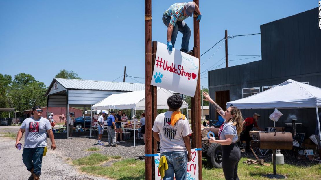 Tyler García, de 21 años, arriba, coloca un cartel durante un lavado de autos y una venta de alimentos para recaudar dinero para las familias de los asesinados.