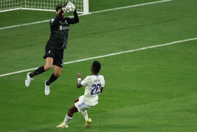 El portero brasileño del Liverpool, Alisson Becker (izq.), salva el balón tras un disparo del delantero brasileño del Real Madrid, Vinicius Junior.