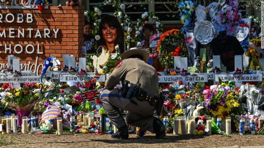 Un agente de policía limpia el memorial provisional antes de la visita del presidente Joe Biden a la escuela primaria Robb en Uvalde, Texas, el domingo.