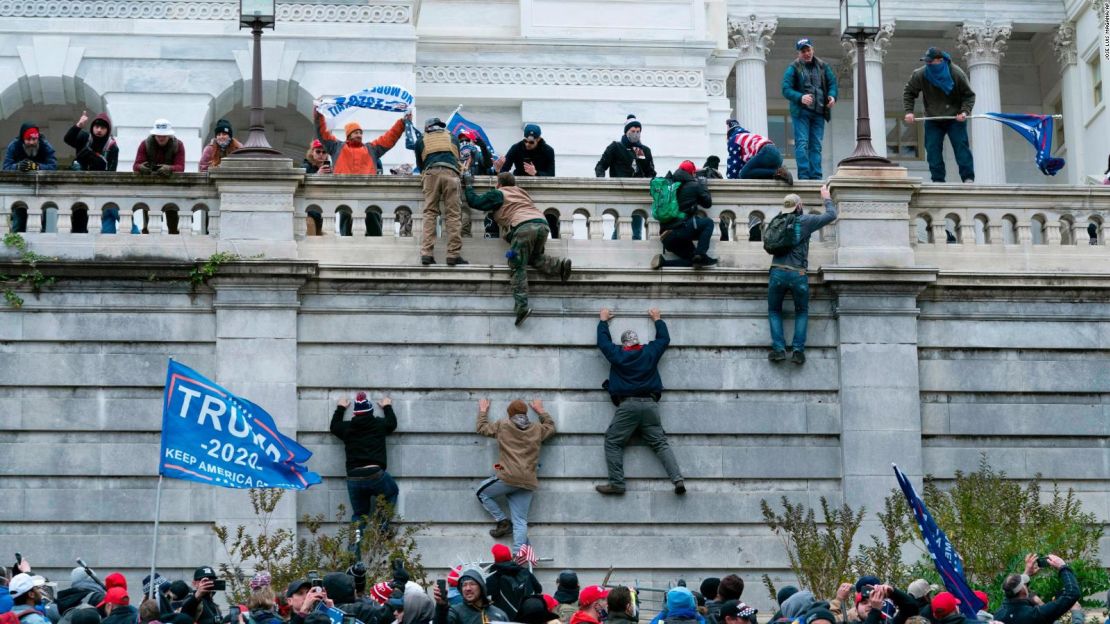 Los partidarios del entonces presidente Donald Trump suben al muro oeste del Capitolio de Estados Unidos, el 6 de enero de 2021.