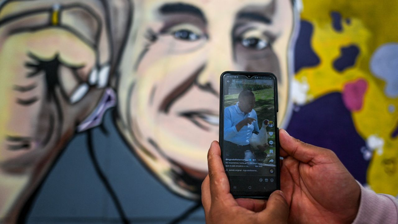 A person looks at the Tik Tok account of Colombian independent presidential candidate Rodolfo Hernandez, in Bogota on June 6, 2022. - Independent businessman Rodolfo Hernandez and former guerrilla and leftist senator Gustavo Petro will face for the Colombia presidency in the June 19 run-off. Hernandez has captured the imagination with his campaign, largely conducted on social media and against corruption, but with a humorous and outlandish tinge, as well as a refusal to debate his opponents. (Photo by Juan BARRETO / AFP)