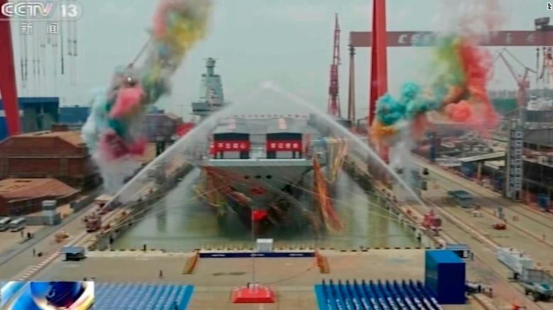 En esta imagen tomada de la cadena estatal de televisión CCTV de China, cañones de agua rocían el tercer portaaviones de China, Fujian, durante su ceremonia de botadura en un dique seco en Shanghái el viernes.