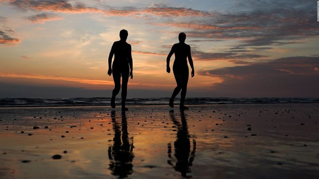 Una pareja de nadadores regresandel mar después de un chapuzón durante el solsticio de verano en Saltburn-by-the-Sea, Inglaterra, el 21 de junio de 2021.