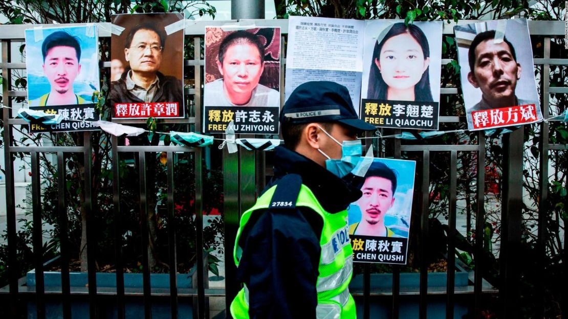 Un agente de policía pasa junto a pancartas que piden la liberación de los activistas chinos de los derechos detenidos, que están pegadas en la valla de la Oficina de Enlace con China en Hong Kong, el 19 de febrero de 2020.