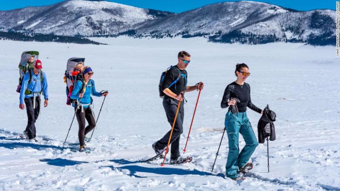 Familias e individuos caminan por un valle cubierto de nieve en el condado de Los Álamos, Nuevo México.