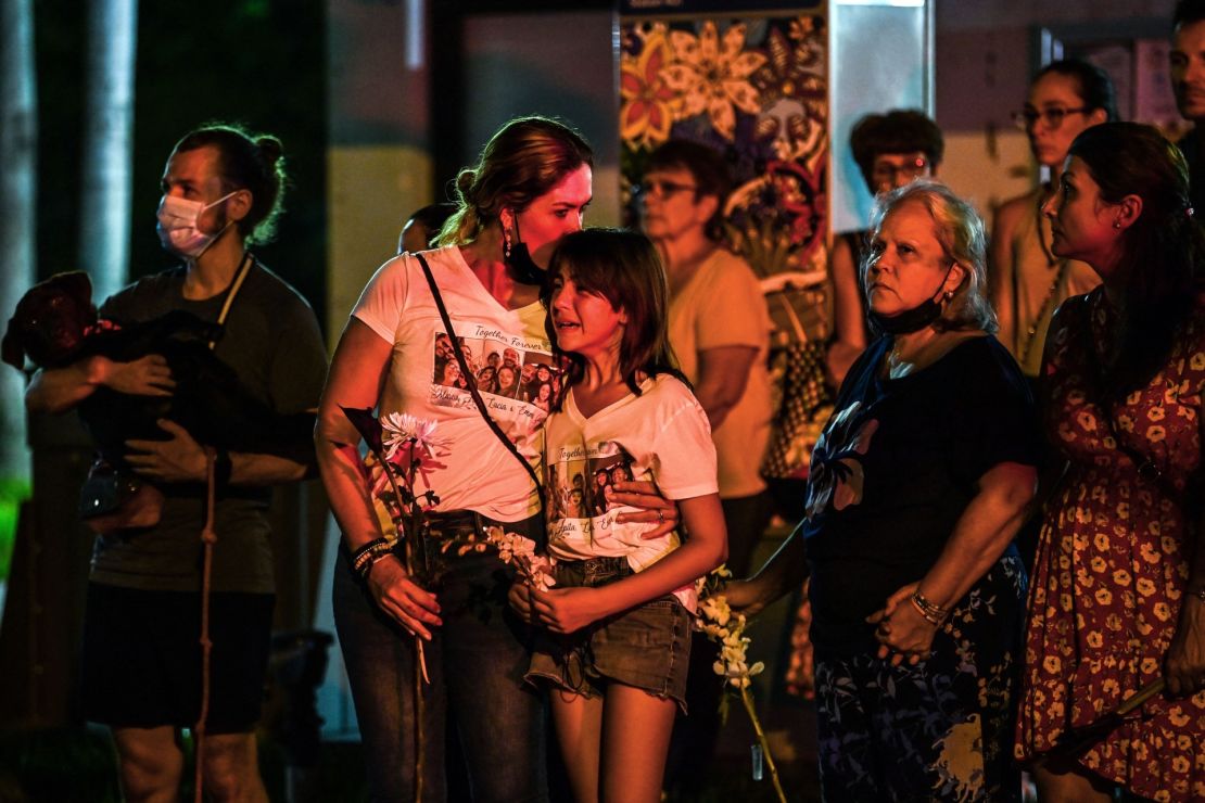 Familiares de las víctimas lloran en el memorial improvisado donde se encontraba el edificio parcialmente colapsado Champlain Towers South en Surfside, Florida, el 24 de agosto de 2021, dos meses después de la tragedia.