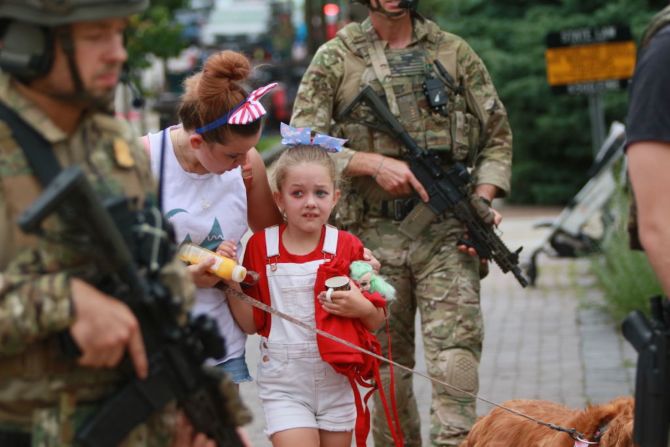 Agentes de policía escoltan a una familia hacia un lugar seguro para alejarlos de la escena de los hechos tras el tiroteo en el desfile del 4 de julio en Highland Park, Illinois.