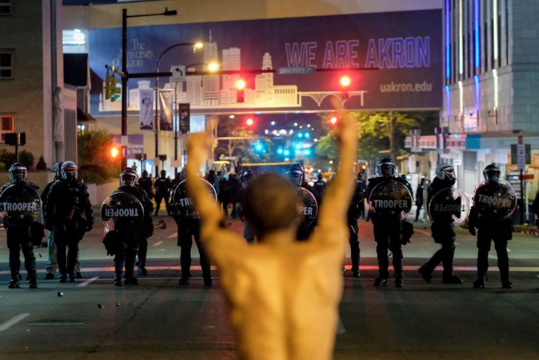 Un hombre hace un gesto hacia los soldados con equipo antidisturbios mientras la policía desplegaba gases lacrimógenos y granadas de aturdimiento para despejar el área alrededor del ayuntamiento de Akron y la estación de policía de Akron durante una protesta por el asesinato de Jayland Walker, baleado por la policía, en Akron, Ohio, el 3 de julio. 2022.