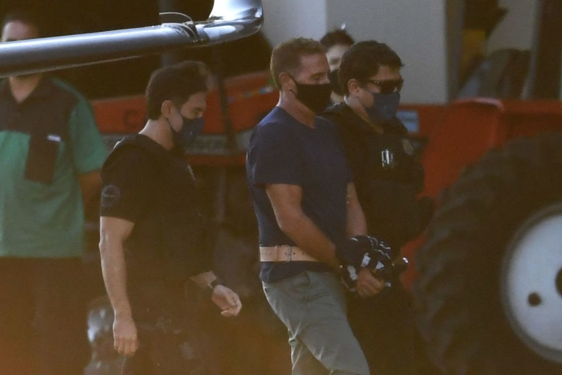 El italiano Rocco Morabito, buscado por narcotráfico y actividades mafiosas, llega a Brasilia el 25 de mayo de 2021 escoltado por policías federales y agentes de la Interpol tras ser detenido ayer en Joao Pessoa, en el estado de Paraiba, noreste de Brasil. - Los fiscales y la policía italianos aplaudieron el martes la captura en Brasil de un importante jefe de la mafia que ha eludido la justicia en Italia durante casi 30 años.