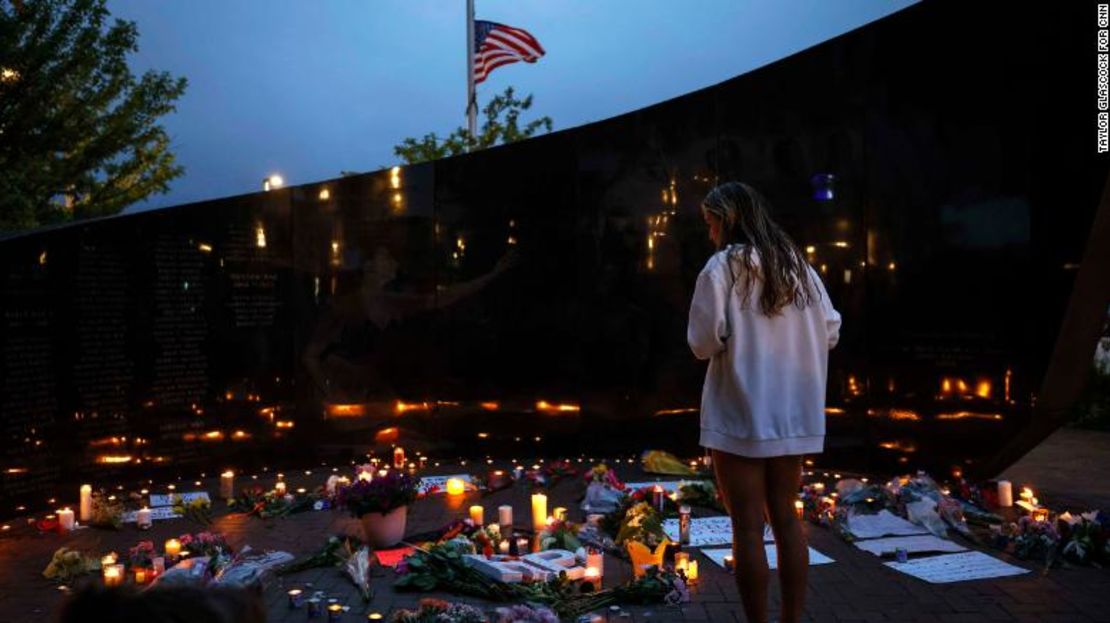Una mujer observa las velas y flores que dejaron las víctimas del tiroteo del desfile del 5 de julio de 2022 en Highland Park.