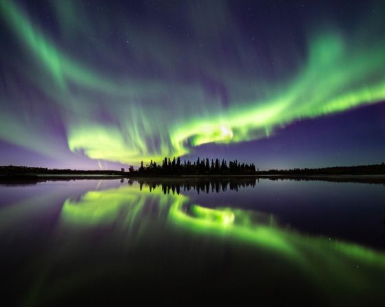 En esta foto, tomada por Shane Turgeon, el verde luminiscente de la aurora boreal se refleja en un gran lago en Alberta, Canadá.