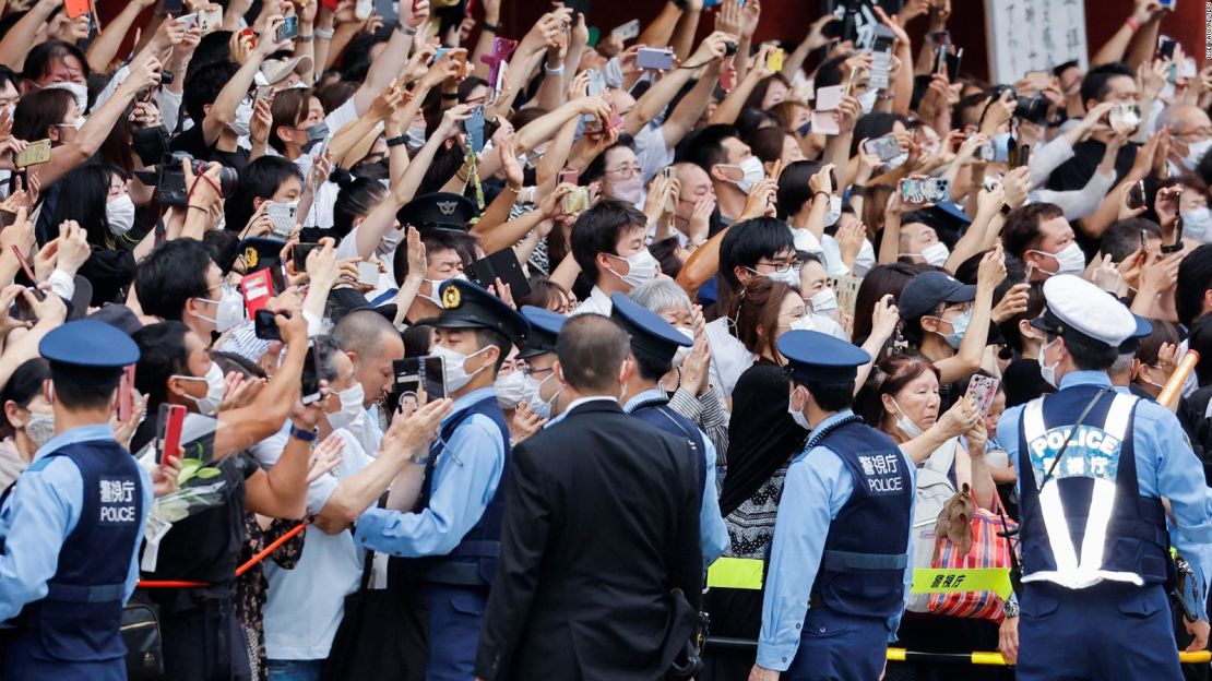 Agentes de policía montan guardia mientras la gente observa una caravana con el cuerpo del difunto ex primer ministro japonés Shinzo Abe en el Templo Zojoji en Tokio el 12 de julio.