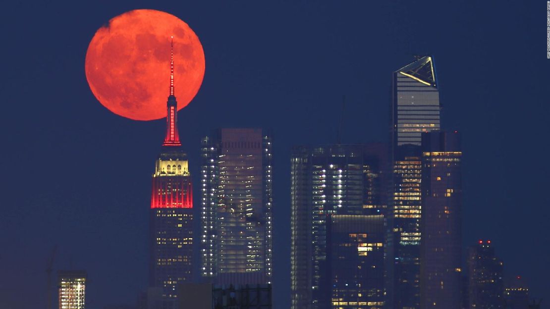 La Luna llena de ciervo, también conocida como “Luna de Trueno” pasa por detrás de Hudson Yards y el Empire State Building mientras sale en la ciudad de Nueva York el 23 de julio de 2021, vista desde Lyndhurst, Nueva Jersey.